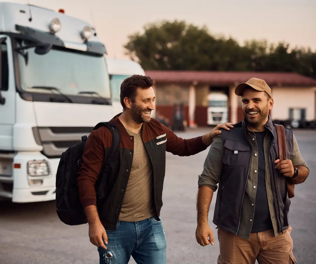 two men in good spirits in a parking lot walk away from the trucks parked in the background